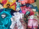 a pile of baby clothes on a bed with a hanger