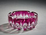un bol en verre violet posé sur une surface blanche, avec une ombre sur cette surface