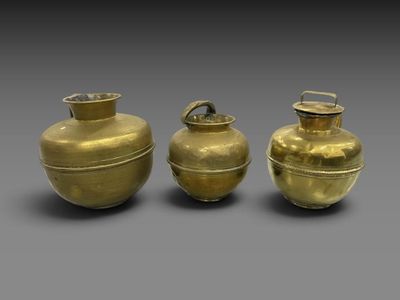 trois vases dorés posés les uns à côté des autres sur une surface grise