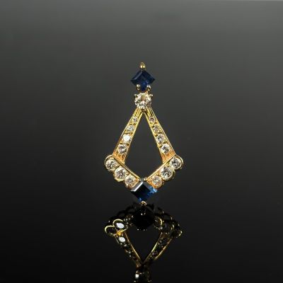 un gros plan d'un pendentif en or et diamants bleus posé sur une surface noire