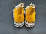 yellow converses with white laces are on a black surface