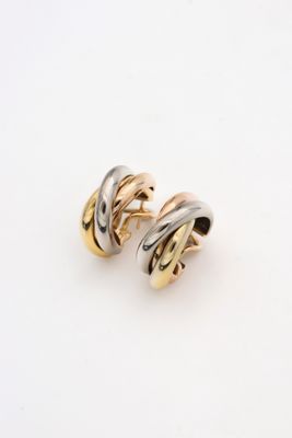 une paire de boucles d'oreilles en or et en argent posées sur une surface blanche
