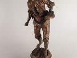 an antique bronze statue of a man holding a basket on a pedestal