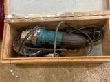 une boîte posée par terre, contenant une perceuse