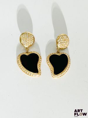une paire de boucles d'oreilles noires et dorées en forme de cœur sur un fond blanc