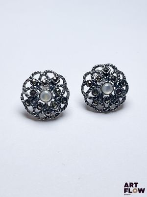 une paire de boucles d'oreilles noires et blanches ornées de perles sur fond blanc