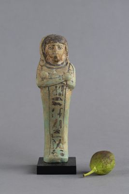 une statue égyptienne représentant un homme tenant un fruit et une poire