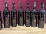 six bottles of wine are lined up on a wooden table