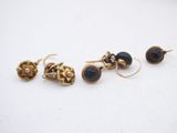 three pairs of gold and black glass earrings on a white surface