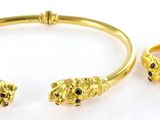 un gros plan d'un bracelet et d'une bague en or posés sur une surface blanche