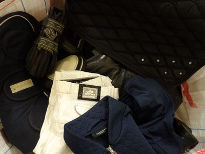 a black bag and a pair of white pants on a bed