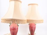 paire de lampes rouges et dorées avec des abat-jours à franges sur fond blanc