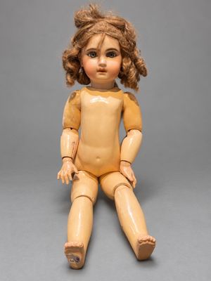 an old wooden doll sitting on a gray surface with a gray background