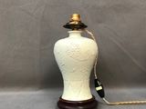 une image représentant un vase blanc posé sur un socle en bois, avec une corde
