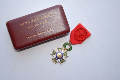 une petite boîte rouge contenant une médaille et un ruban rouge