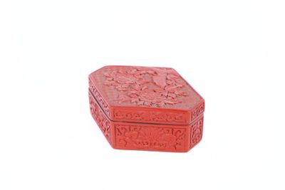 une petite boîte rouge posée sur une surface blanche