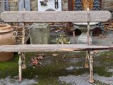 un banc en bois posé devant un bâtiment en pierre