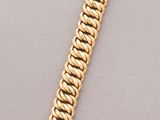 a gold bracelet with a clasp on a gray surface