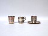 three silver cups and saucers are sitting on a white surface