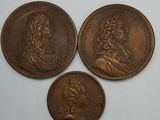 trois médaillons en bronze représentant deux hommes, dont l'un est un buste et l'autre est un buste
