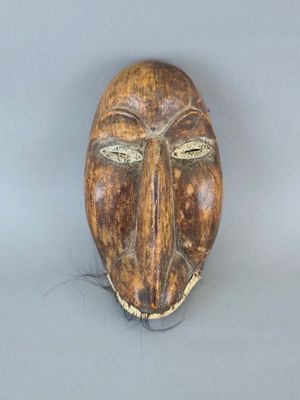 une image représentant un masque en bois sur une surface grise