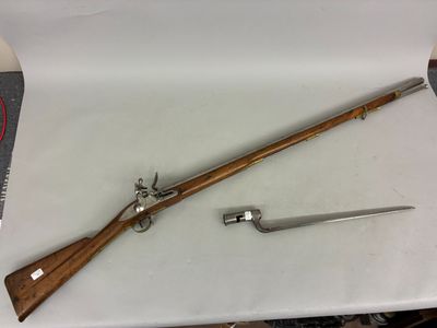 an old rifle with a wooden handle and a knife on a table