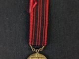 a close up of a medal on a black surface with a red ribbon