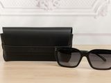 black sunglasses and case on a table with a white wall