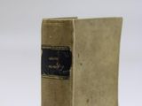an old book sitting on top of a white table next to a white wall