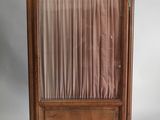 une vieille armoire en bois surmontée d'un rideau