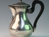 a silver coffee pot with a black handle on a table