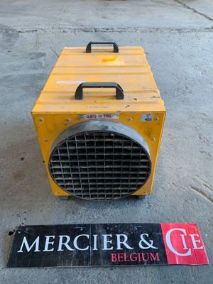 a yellow heater sitting on the ground next to a sign