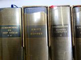 plusieurs vieux livres sont alignés sur une étagère dans une bibliothèque