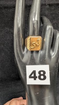 Quelqu'un tient une bague en or posée sur un mannequin portant le numéro 48.