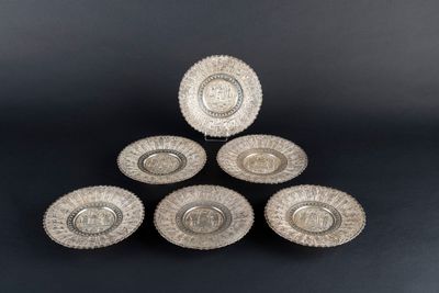 a set of four silver plated dishes on a black background