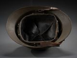 an old military helmet with a leather strap on a gray background