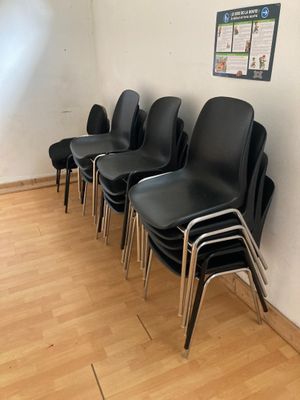 Plusieurs chaises noires sont alignées contre un mur dans une salle d'attente