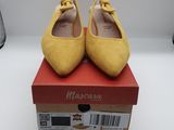 des chaussures jaunes ornées de nœuds, posées sur une boîte