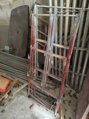 a pile of metal pipes and a ladder in a room