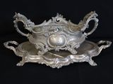 an antique silver plate with a bowl and tray on a black background