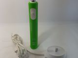 une brosse à dents électrique verte et un chargeur posés sur une table blanche