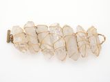 a close up of a gold wire bracelet with white crystals on it