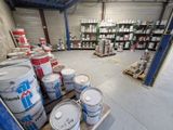plusieurs seaux de peinture posés sur une palette dans un entrepôt