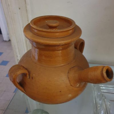 un grand vase marron posé sur une table en verre