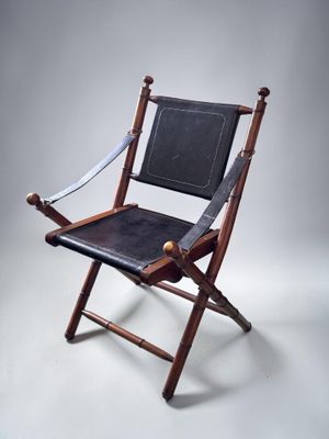 an old folding chair with a leather seat on a white background