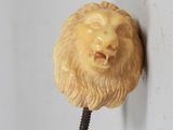 une tête de lion accrochée au mur, avec une vis plantée dedans