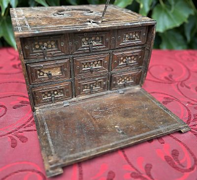 une petite boîte en bois avec des tiroirs posée sur une nappe rouge