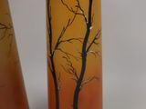 two vases with trees painted on them sitting on a table
