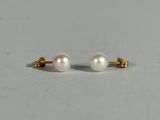 a pair of pearl earrings on a white surface