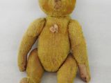un petit ours en peluche jaune assis sur une surface blanche
